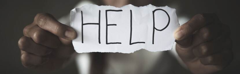 Iemand houdt een papier vast waarop 'help' staat geschreven